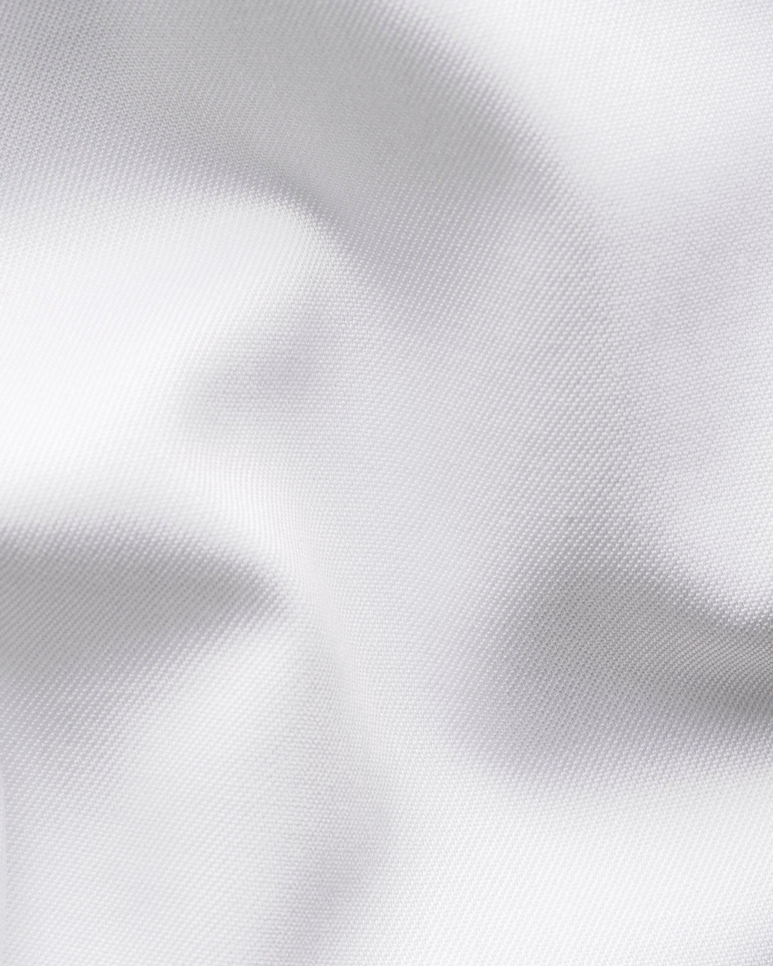 Close-up of smooth, white Signature Twill fabric with subtle folds and a soft texture, featured on the Slim Cut Away Medallion Effect Signature Twill Shirt by Eton.