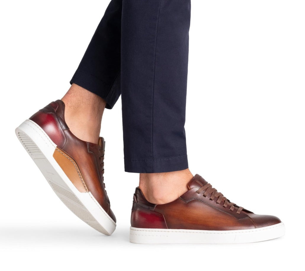 Person wearing dark brown Magnanni Amadeo Sneaker leather sneakers with white soles and navy blue pants, embodying contemporary cupsole fashion.