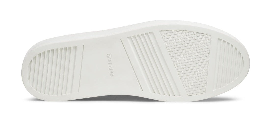 The image showcases the sole of a white Magnanni Amadeo Sneaker featuring multiple textured grips and the brand name "MAGNANNI" embossed in the center, epitomizing contemporary cupsole fashion.