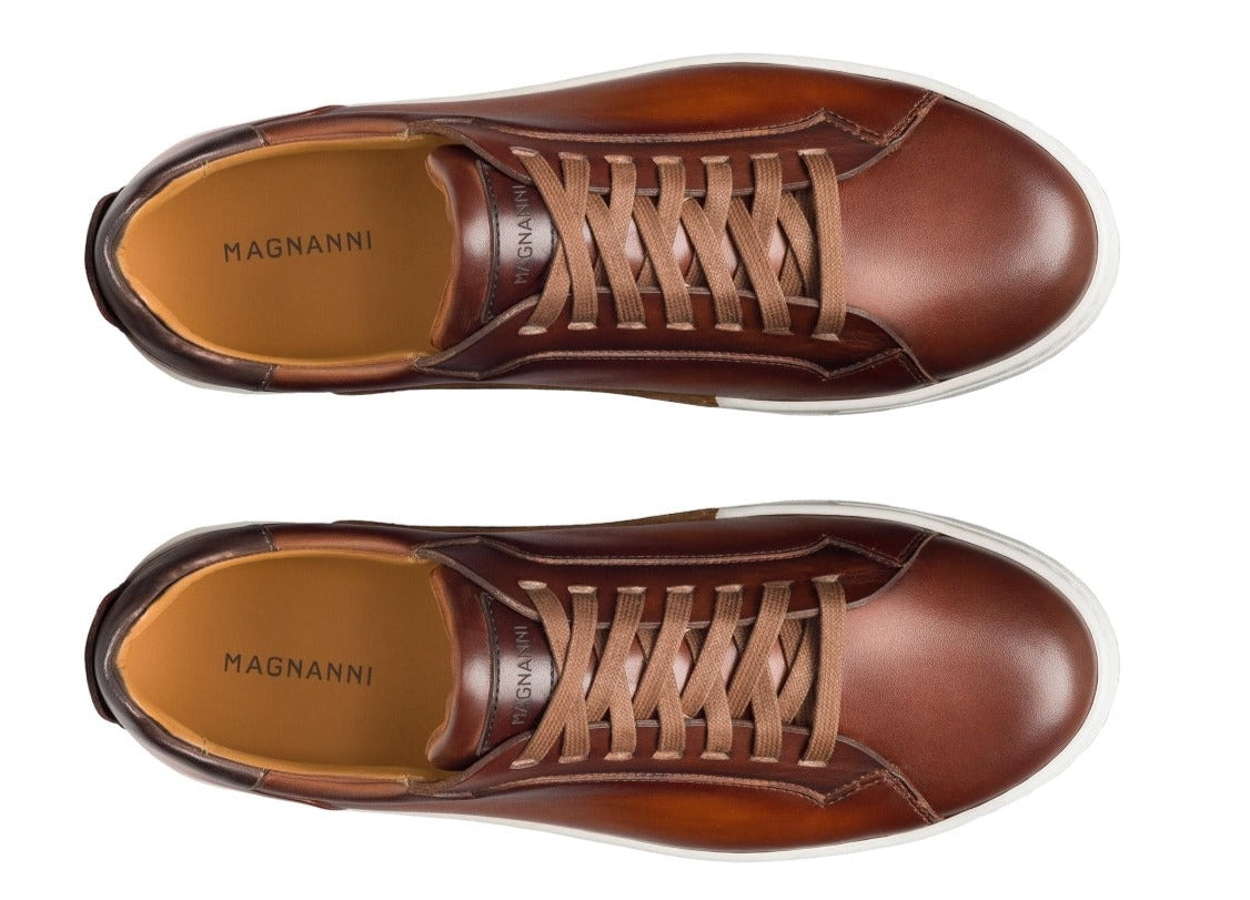 Top view of a pair of Magnanni Amadeo Sneakers in brown leather with white soles and brown laces. The brand name Magnanni is visible on the insole, reflecting the essence of contemporary cupsole fashion.