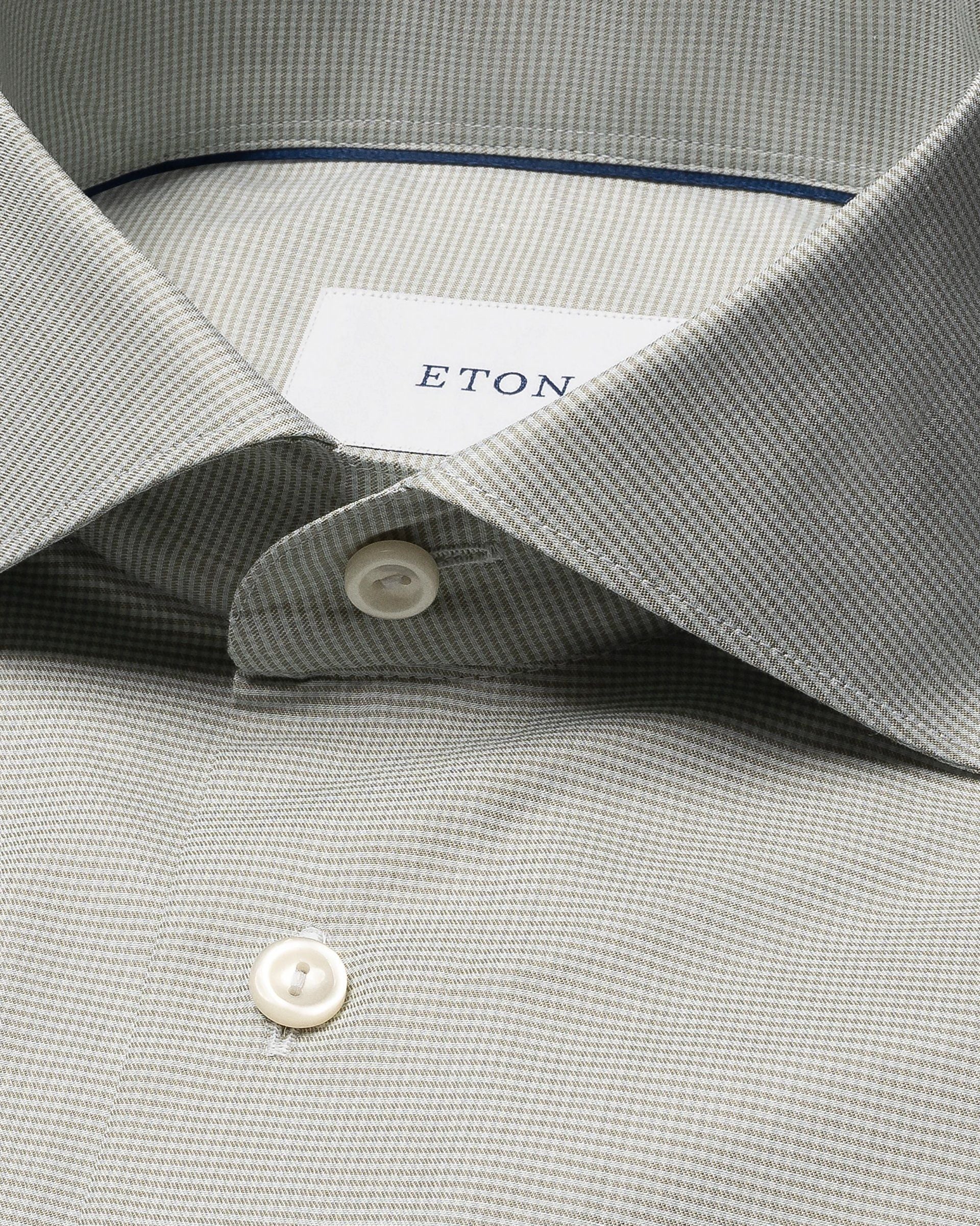 Close-up of the Eton Slim Wide Spread Micro Check Twill Shirt in light grey, featuring a subtle micro check pattern, white buttons, and the signature brand label inside the collar.