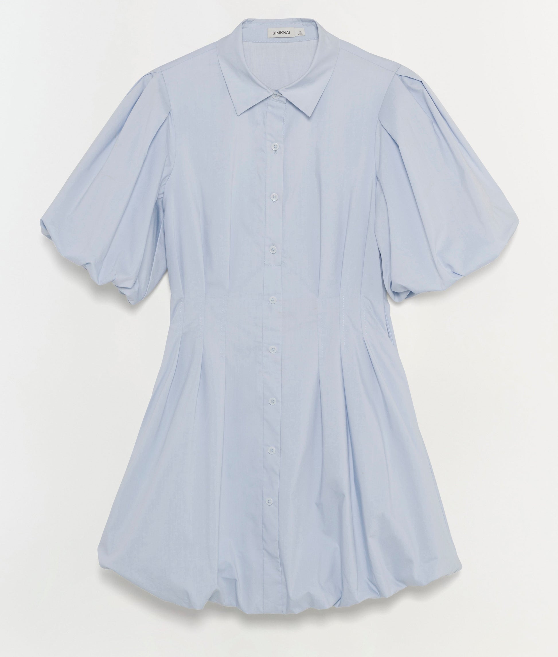 The Cleo Dress by Simkhai is a light blue cotton mini dress featuring a collar, button-down front, pintuck details at the pleated waist, and slightly puffed sleeves, shown against a plain white background.