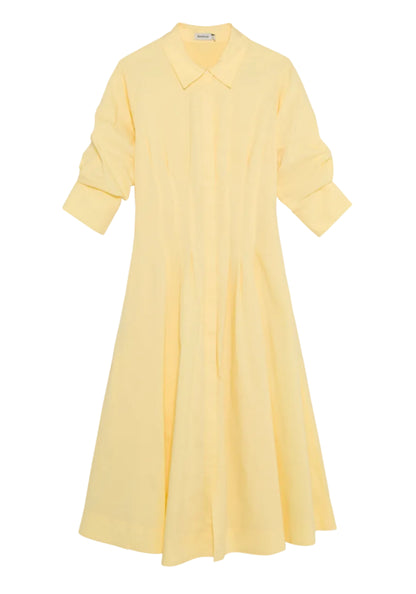 The Simkhai Jazz Pintuck Midi Dress, in light yellow cotton poplin, features a collar, long sleeves with button details, and an A-line silhouette, shown laid flat on a white background.
