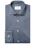 A neatly folded blue Slim Wide Spread Filo di Scozia Knit Shirt by Eton, featuring a classic collar, white buttons, and a visible "ETON" label inside the collar.