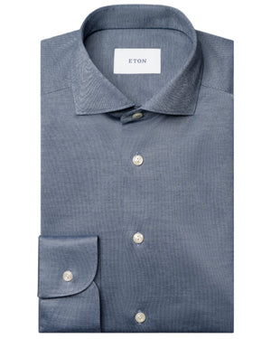A neatly folded blue Slim Wide Spread Filo di Scozia Knit Shirt by Eton, featuring a classic collar, white buttons, and a visible "ETON" label inside the collar.