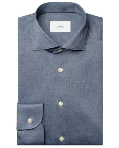 A neatly folded blue Slim Wide Spread Filo di Scozia Knit Shirt by Eton, featuring a classic collar, white buttons, and a visible "ETON" label inside the collar.