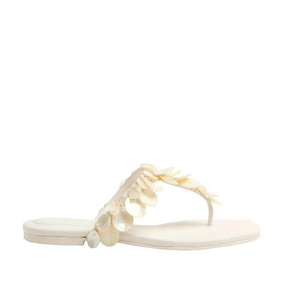 The Elin Natural Shell Beaded Thong Sandal by Simkhai is a cream flat sandal with a thong design, adorned with decorative beaded shell accents on the strap.
