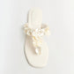 The Simkhai Elin Natural Shell Beaded Thong Sandal is a white flat sandal featuring an open toe and a thong silhouette, adorned with layered, round shell-like beaded embellishments on the strap.