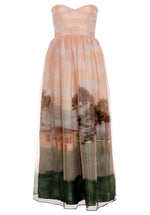 The Tonia Dress by Agua By Agua Bendita is a strapless, floor-length gown with a fitted bodice and full skirt, featuring a scenic landscape print—ideal for your next formal occasion.
