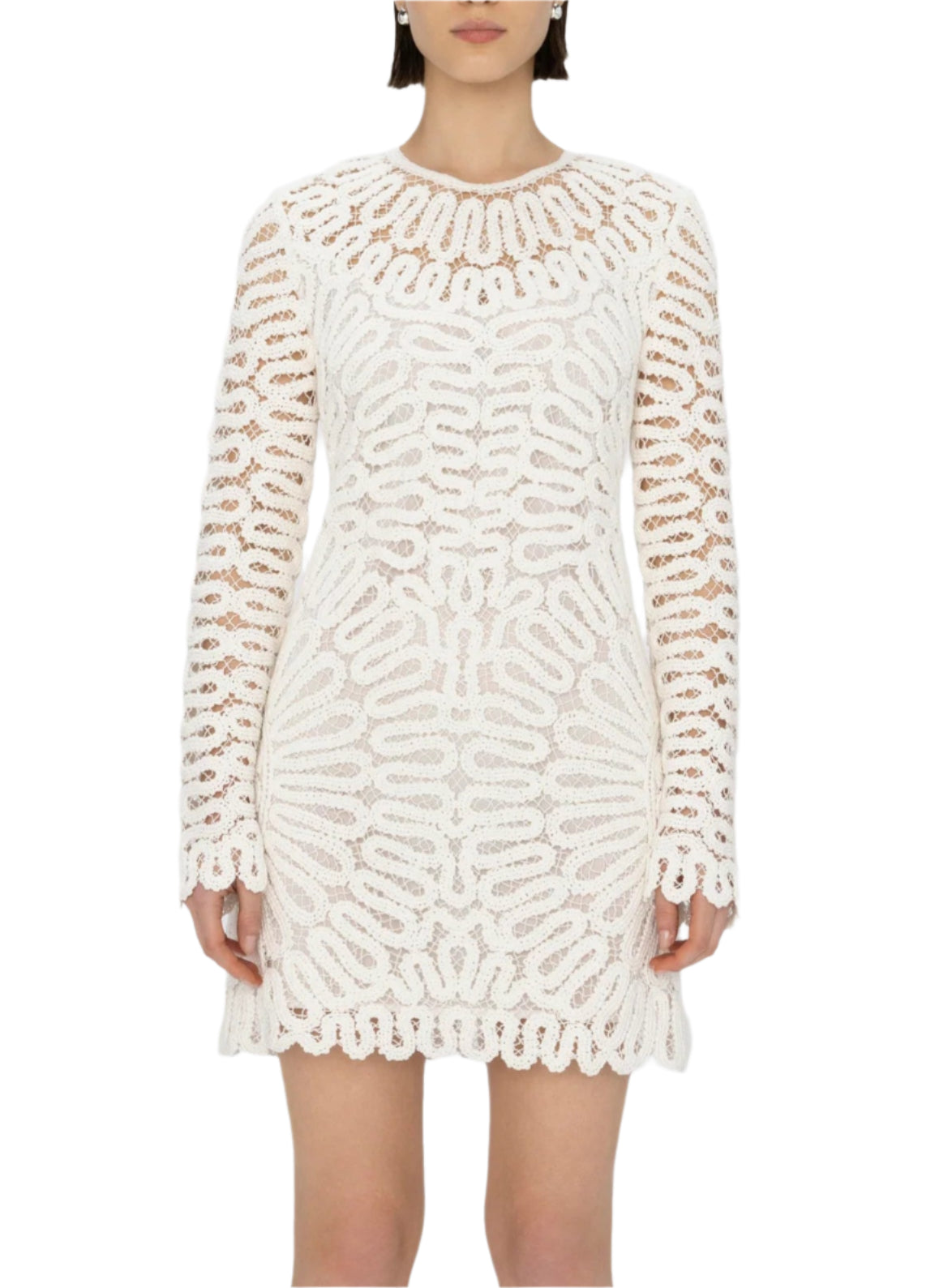 A woman wears the McCall Mini Dress by Simkhai, featuring white lace, a lined bodice, sheer sleeves, and crochet embroidery, standing against a plain background.