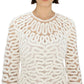 A woman models the Simkhai McCall Mini Dress, featuring white long sleeves with intricate crochet lace embroidery and a looped pattern, shown from shoulders to just above the waist.