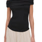 A woman models the Simkhai Adaline Off Shoulder Midi Dress, showcasing a fitted bodice and black off-the-shoulder top with a flowing skirt, captured from shoulders to hips against a plain backdrop.