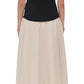 A woman stands facing away, wearing the Simkhai Adaline Off Shoulder Midi Dress with a black sculpted bodice and beige skirt, styled with black heeled sandals.