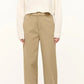 A person wears the Staud Cropped Hampton Cashmere Sweater in cream chunky knit, paired with high-waisted beige wide-leg trousers and black shoes, standing against a plain background.