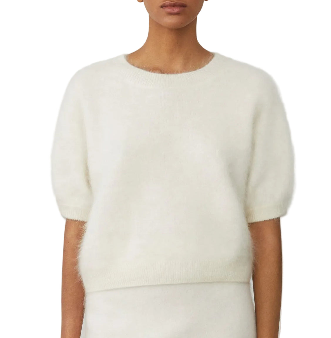 A person wearing the Lisa Yang Juniper Brushed Cashmere Sweater in white, a short-sleeve, cropped style, paired with a matching skirt and shown from shoulders to hips against a plain background.