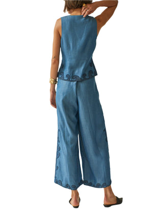A person wearing the Carolina K Rebekka Vest with front button closure and matching wide-leg pants featuring black swirl hem patterns stands with one arm raised, turned away from the camera.
