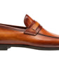 The Daniel Loafer by Magnanni is a classic penny loafer crafted in rich brown leather, featuring a sleek penny strap atop the smooth upper. Highlighted against a white background, it offers Línea Flex technology for all-day comfort, blending sophistication with timeless style.