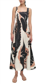 A woman models the Simkhai Paola Midi Dress, a sleeveless maxi with an abstract black, beige, and white print. The flattering silhouette pairs beautifully with her flat, tan sandals.