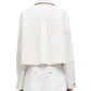 A person is seen from behind wearing a Maria McManus white Cropped Swing Jacket and pants. This elegant jacket features an oversized collar, long sleeves, and is made from organic cotton for a chic, sustainable style.