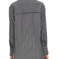 Person wearing an oversized tunic shirt with a vintage-inspired black and white stripe, collar, and pleated yoke detail from Maria McManus, paired with white silky cotton cupro pants.