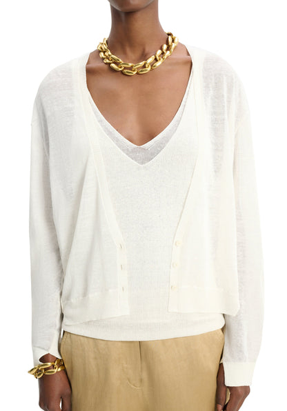 A person is wearing a white, semi-sheer Dorothee Schumacher Summer Ease Cardigan over a matching top, accessorized with a chunky gold necklace and bracelet, and beige pants.