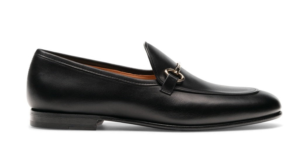 The Magnanni Stella Loafer from Magnanni is a sophisticated black leather apron toe loafer, highlighted by a metal bit on the front and complemented with a low heel, offering timeless elegance through its slip-on design.