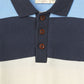 A close-up of the Copenhagen Colors Baby Boys’ and Boys’ Striped Pique Long Sleeved Polo with blue, navy, and cream stripes and three brown buttons on the placket.