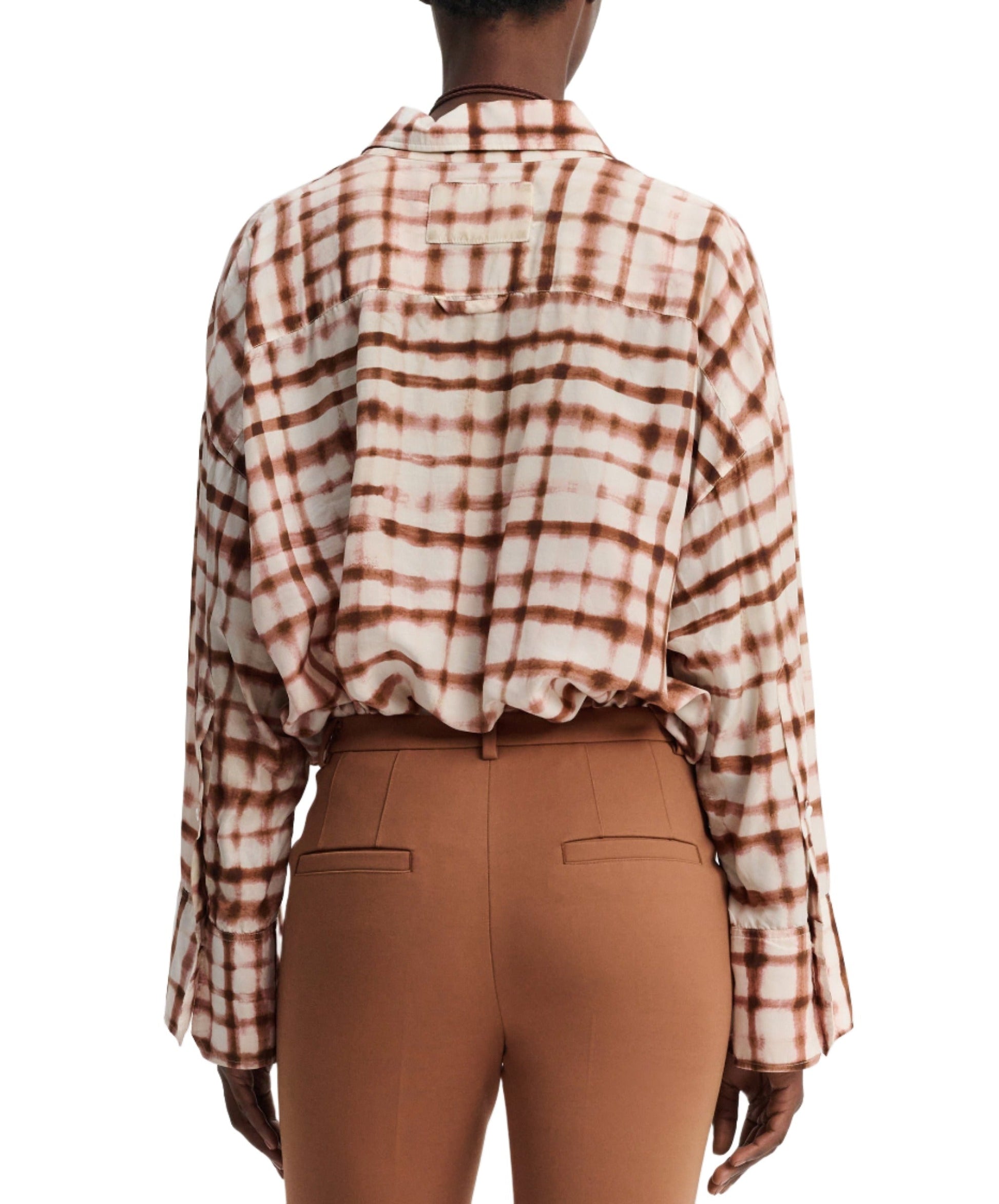 Rear view of a person wearing a Dorothee Schumacher Checked Statement Blouse featuring an oversized plaid design in shades of brown and white, paired with silk-infused brown pants.