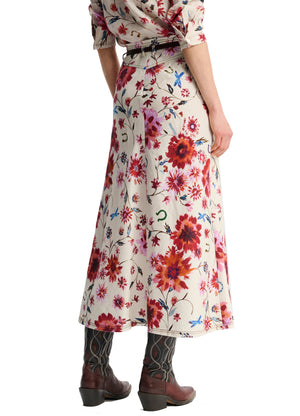 The person is wearing the Dorothee Schumacher Floral Ease Skirt with rolled-up sleeves, brown leather boots, and a chic leather tie belt, viewed from the side.