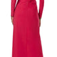 A person is seen from the back wearing Monique Lhuillier's Jewel Neck Long Sleeve Draped Gown in bright pink matte jersey, featuring a floor-length silhouette, zipper closure, and gathered waist detail.