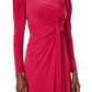 A person wears the Monique Lhuillier Jewel Neck Long Sleeve Draped Gown, featuring a bright pink matte jersey, draped fabric, gathered and twisted waist detail, high neckline, and a high slit for added flair.