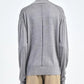A person wears the Maria McManus Fine Gauge Mock Neck Sweater in light heather grey, featuring a center back seam, paired with beige pants and standing against a plain background.