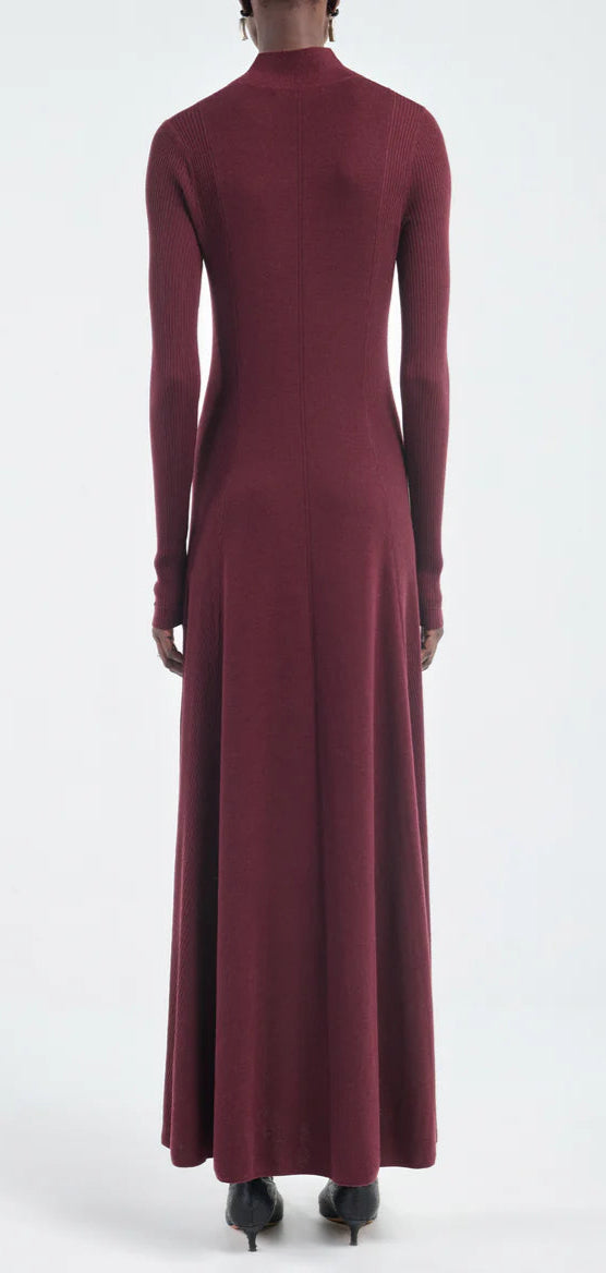 Model shown from the back wearing the Maria McManus Rib Godet Dress in merlot, an ankle-length, long-sleeved design, set against a plain light background.