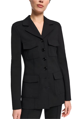 A person is wearing the Dorothee Schumacher Emotional Essence Jacket, a black tailored blazer with notched lapels and four pockets, featuring button closure. This stylish piece combines Punto Milano fabric for a sophisticated shirt-jacket hybrid look.