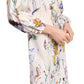 A person is wearing the Dorothee Schumacher Floral Power Maxi Dress, a long-sleeved, colorful floral printed linen dress featuring a charming lace-up front.