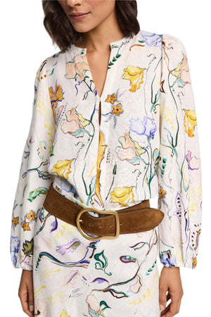 A person wearing the Dorothee Schumacher Floral Power Blouse, featuring voluminous sleeves and a floral pattern, cinched at the waist with a wide brown belt.