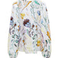 The Dorothee Schumacher Floral Power Blouse, by Dorothee Schumacher, features a modern twist with its V-neckline, long puffed sleeves, and printed linen design adorned with colorful floral and leaf patterns.