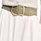 A person wears a light gray sweater with a white skirt, accented by Dorothee Schumacher's Suede Sensation Belt in olive green suede with a large gold buckle and chic curved design.