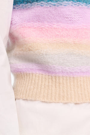 Close-up of the Luxury Love Top by Dorothee Schumacher, featuring textured knit with horizontal pastel stripes in pink, purple, blue, cream, and beige, partially covered by a white garment.
