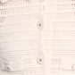 Close-up of the Dorothee Schumacher Precise Pointelle Jacket—a cream-colored, crocheted shirt with a graphic pointelle pattern, four buttons, and two chest pockets, worn by a person.