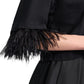 Model wears the Dorothee Schumacher Feminine Favorites Shirt, a black boxy cotton tee with ostrich feather-trimmed sleeves, paired with a black skirt. Shown from shoulder to waist against a white background.