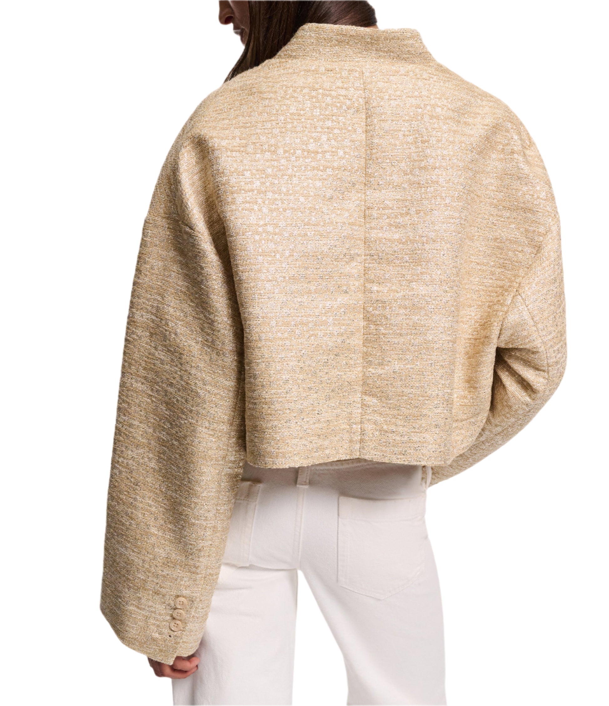 A person wears Dorothee Schumacher’s Shiny Coolness Jacket—a textured, light gold Lurex-tweed piece with a boxy silhouette and long sleeves—paired with off-white pants, shown from the back against a white background.