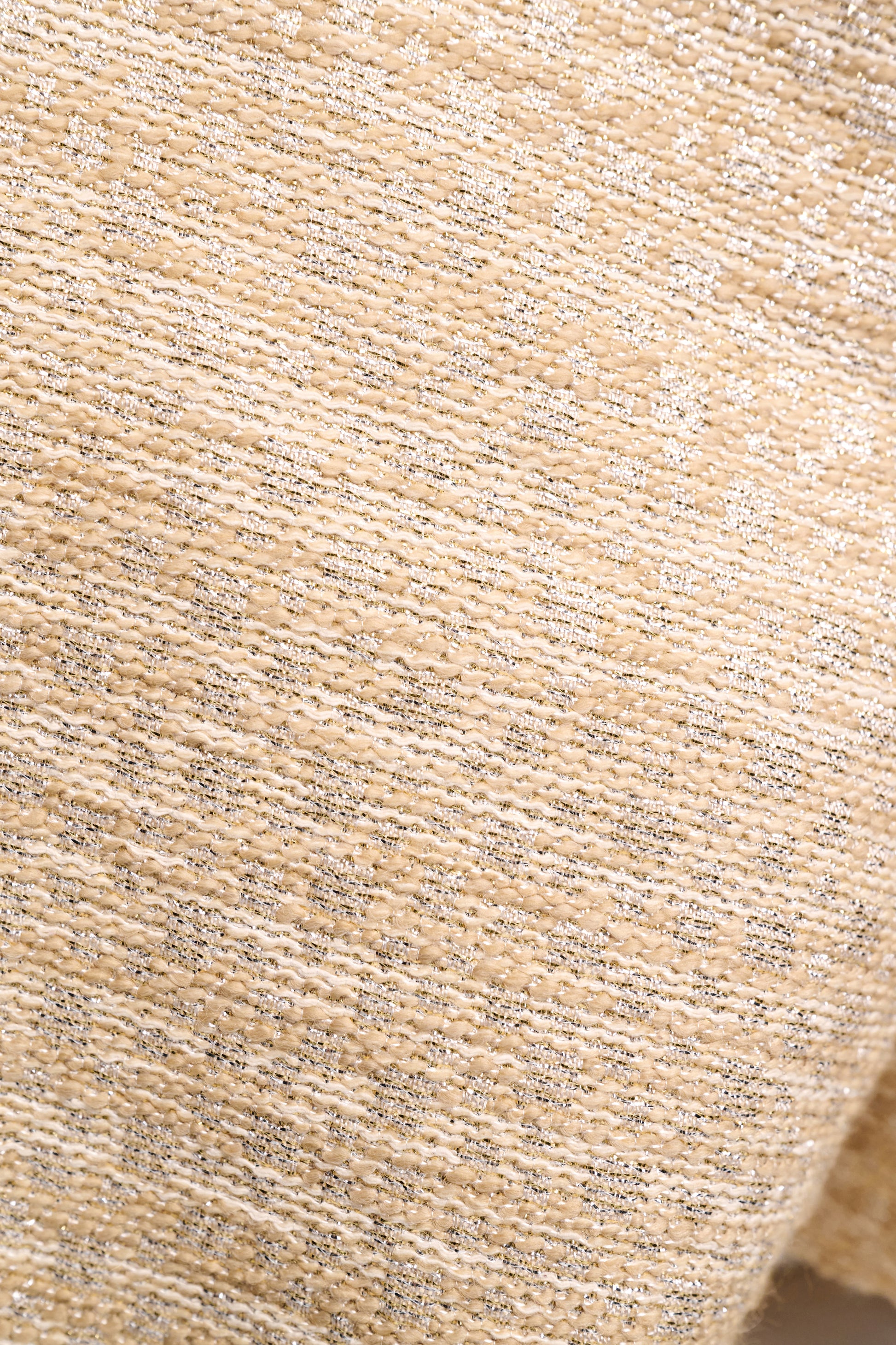 Close-up of the Shiny Coolness Jacket by Dorothee Schumacher, featuring textured beige fabric with a subtle metallic sheen and an elegant woven pattern, ideal for stylish jackets or shift dresses.