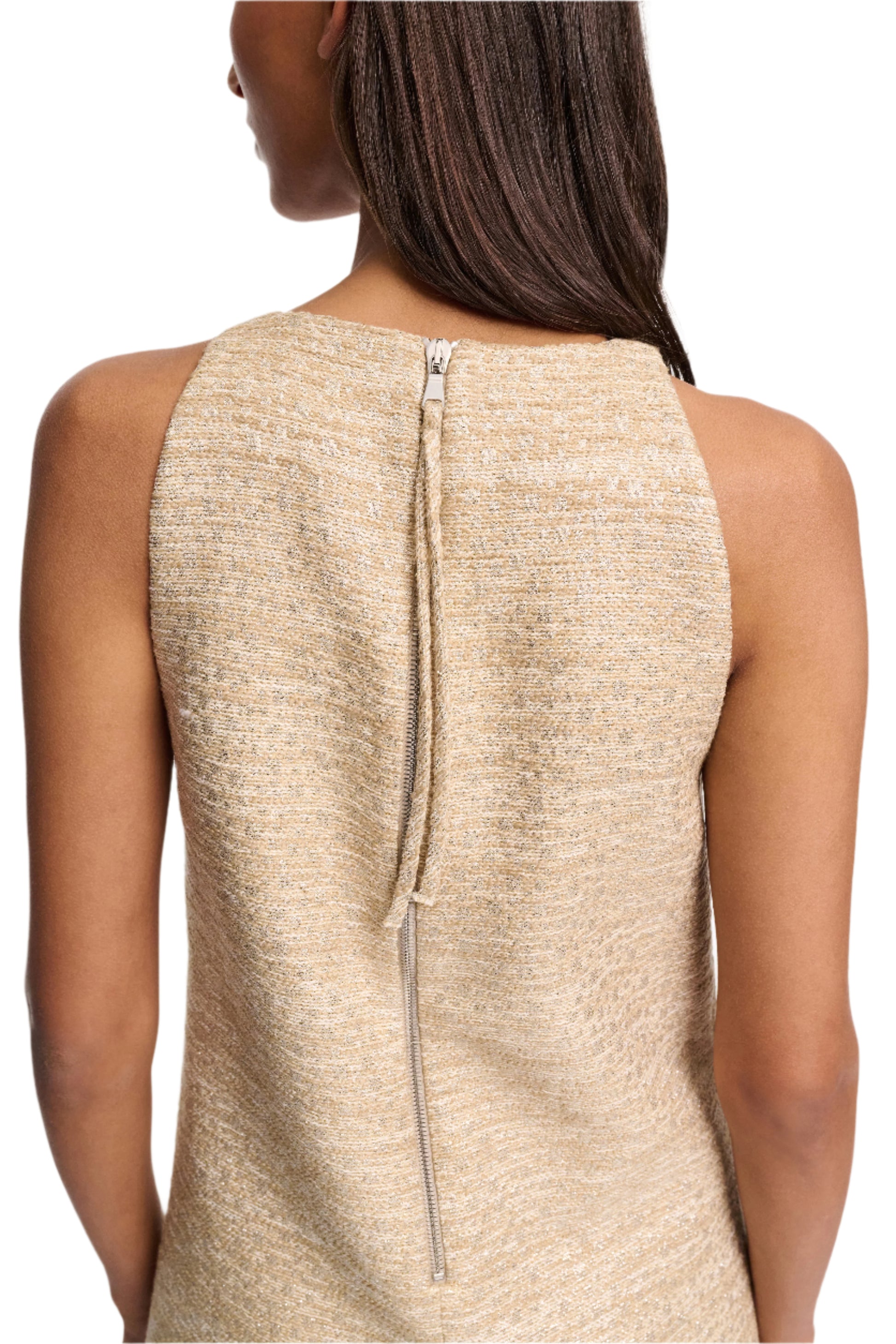 A woman is seen from behind wearing the Dorothee Schumacher Shiny Coolness Dress, a sleeveless, textured beige Lurex-tweed shift with an exposed silver zipper down the center.
