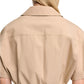A person with long blonde hair is shown from the back wearing Dorothee Schumacher’s Poplin Power Cropped Blouse—a beige, short-sleeved cotton poplin top featuring an open collar and elastic cinched waist.