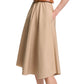 A woman poses with one hand on her hip, wearing the Dorothee Schumacher Poplin Power Dress—a beige cotton shirtdress with a tailored waist, tan belt, and cream ankle-strap flats.