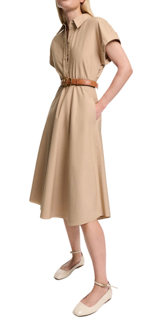 A woman poses with one hand on her hip, wearing the Dorothee Schumacher Poplin Power Dress—a beige cotton shirtdress with a tailored waist, tan belt, and cream ankle-strap flats.