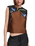 Woman wears the Soft Petal Top by Dorothee Schumacher—a sleeveless brown and black crop with blue floral print—paired effortlessly with black drawstring pants, evoking Italian-inspired artistry.