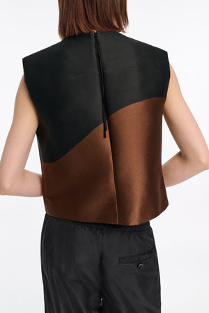 A person wears the Dorothee Schumacher Soft Petal Top—sleeveless, black and brown cloque jacquard with a back zipper—paired with black pants. The Italian fabric artistry is highlighted as they're shown from behind against a plain background.