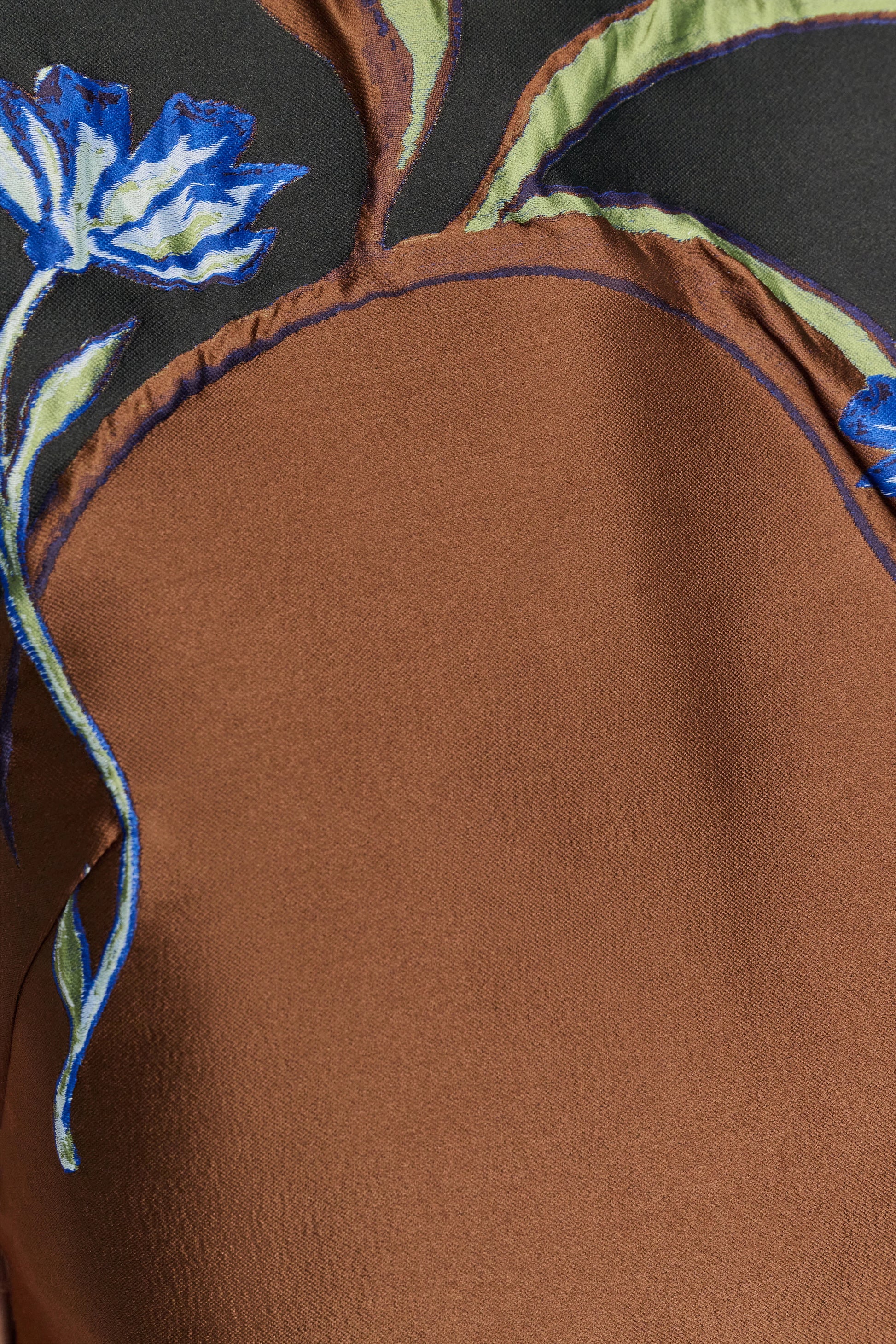 Close-up of the Soft Petal Top by Dorothee Schumacher, featuring brown cloque jacquard with blue floral embroidery and green leaf accents on a black background, highlighting exceptional Italian craftsmanship.